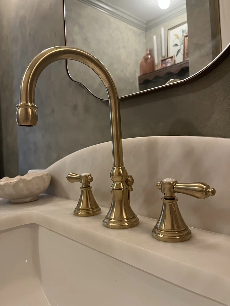 A brass faucet set against veined stone.